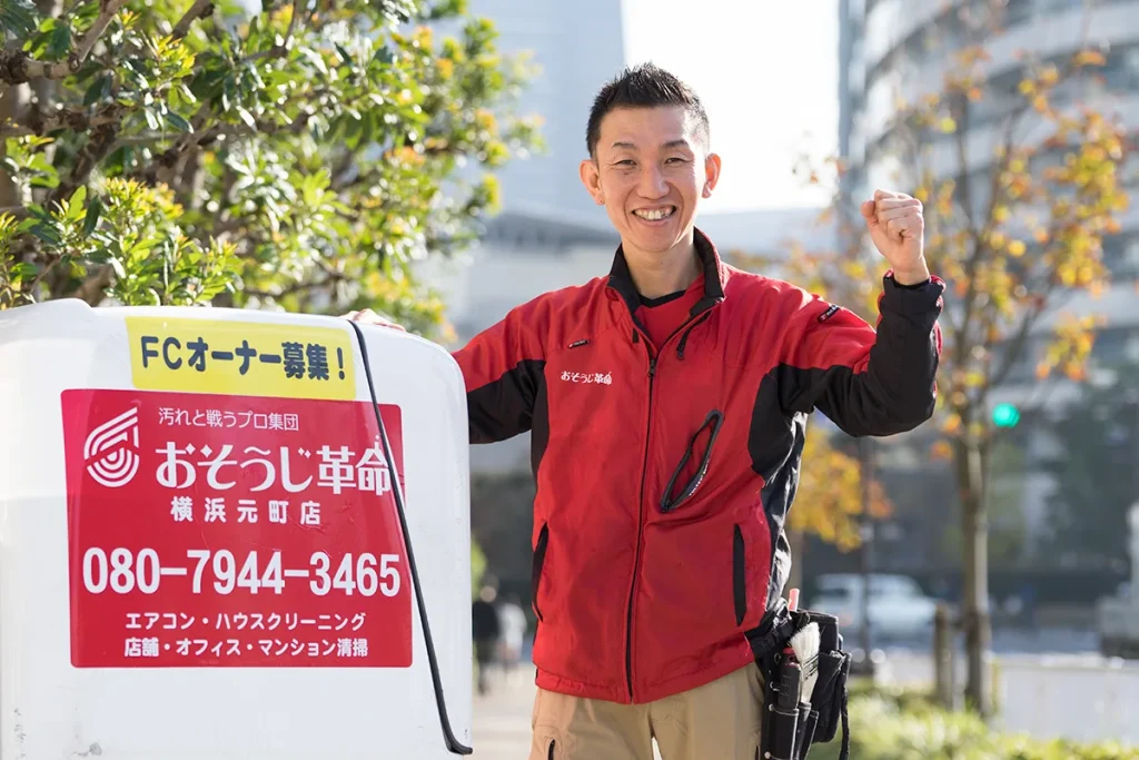 エアコンクリーニングの現場で笑顔でガッツポーズをするハウスクリーニングスタッフの男性