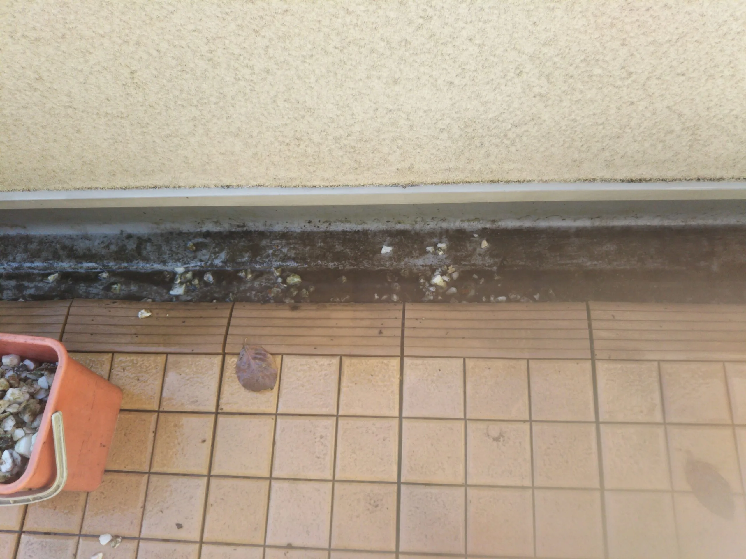 汚れの付着した窓のサッシレールとバケツが写った清掃前の写真