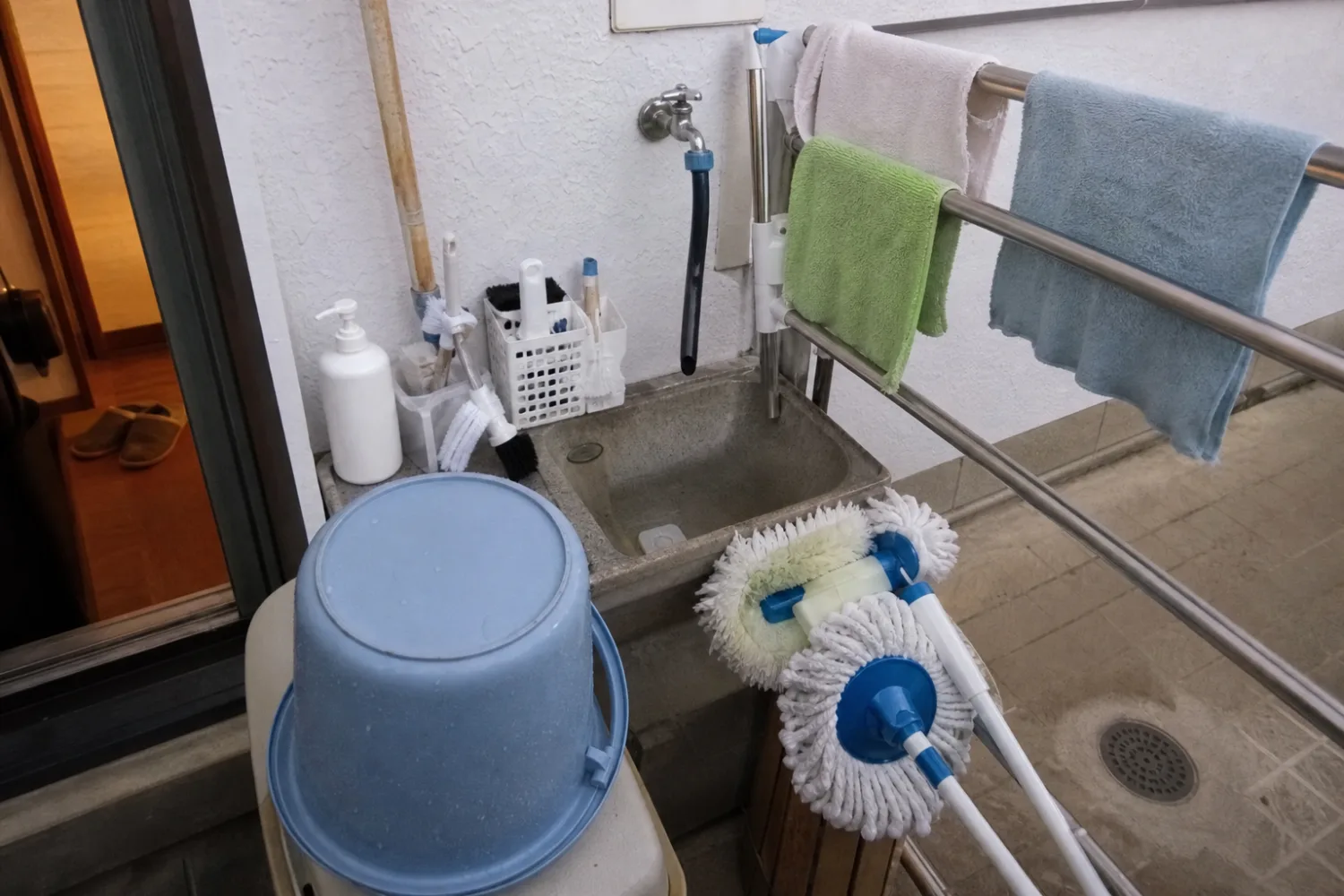 外流しでブラシやバケツなど清掃道具を洗って手入れしている様子
