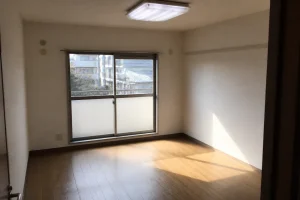 家具のない空室の洋室。フローリングに窓からの光が差し込んでいる